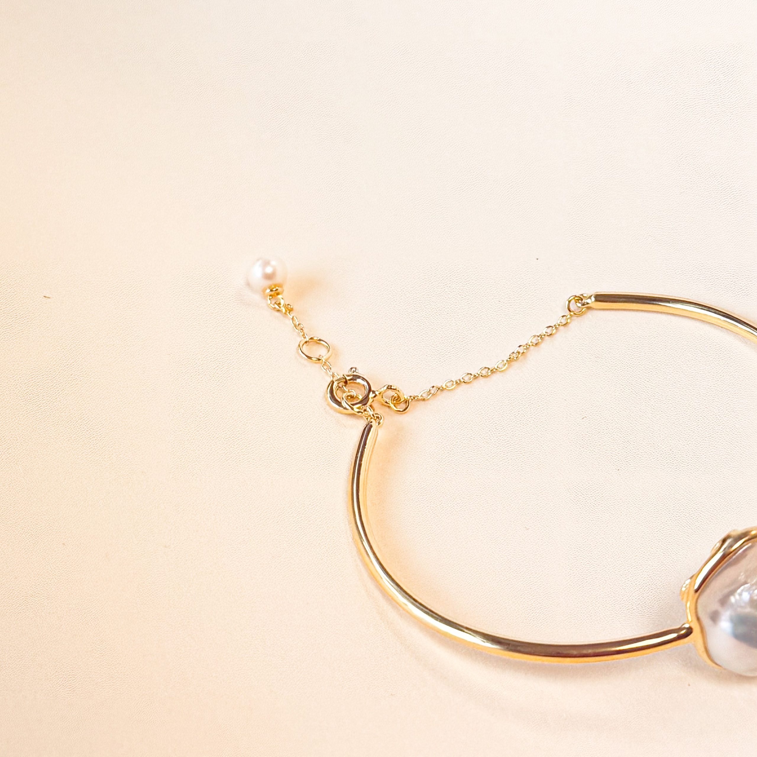 Profile view of Gold Vermeil Bangle showing asymmetrical chain and round pearl detail