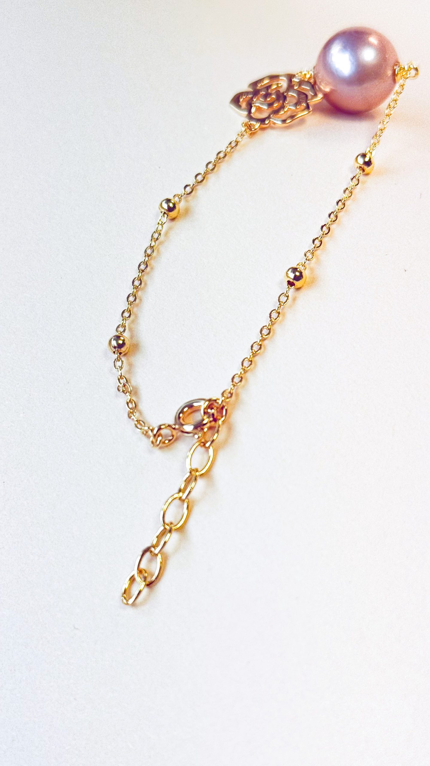 Close-up of the 18K gold plating texture and the natural luster of the pink freshwater pearl.