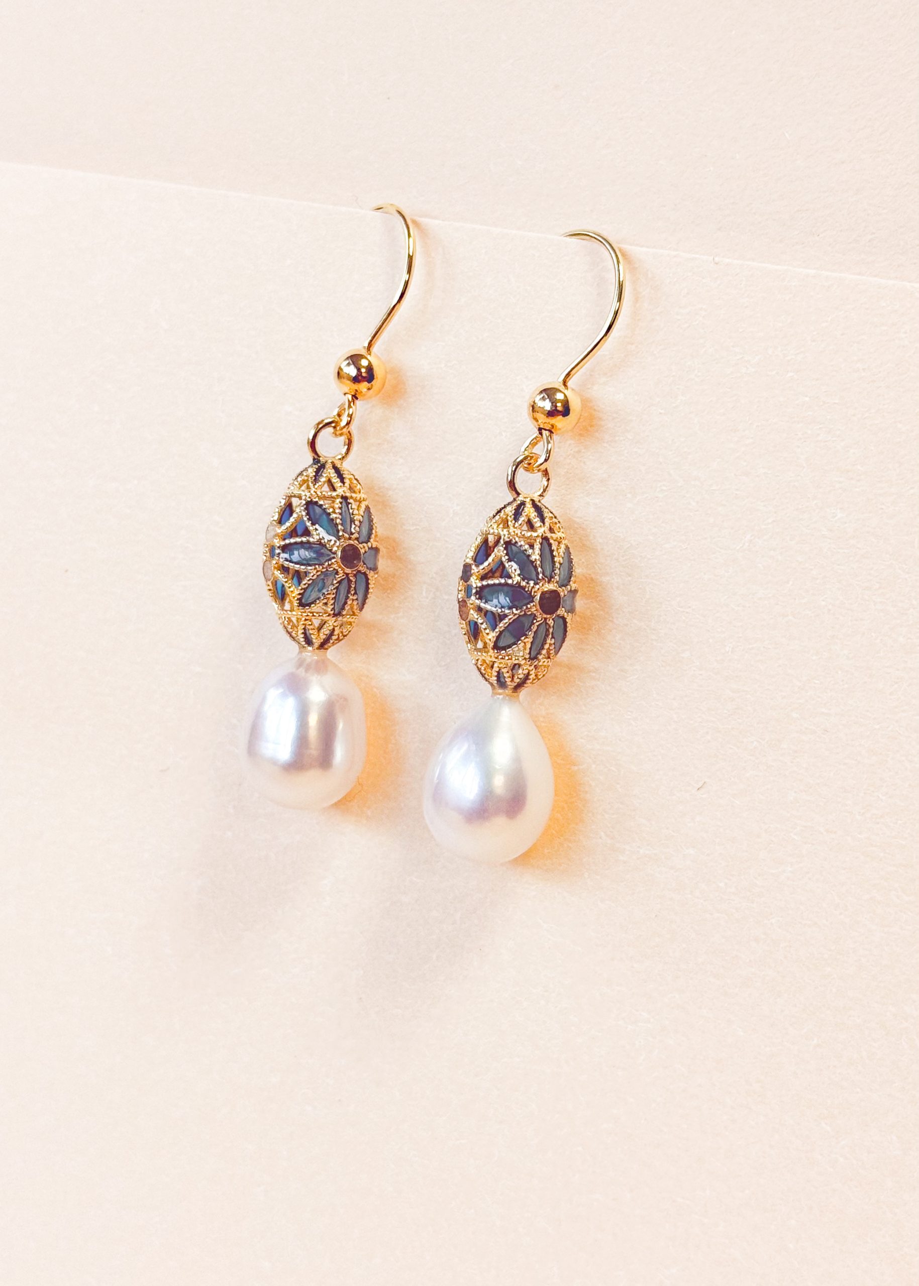 Close-up of the hand-filled blue enamel detailing on geometric gold vermeil earrings.